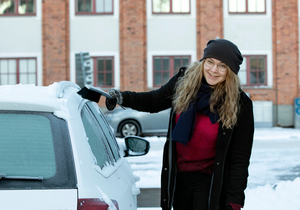 Kvinna tar bort snö från bilen