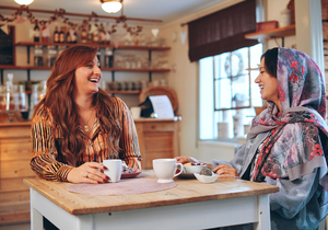 Två kvinnor skrattar på ett café
